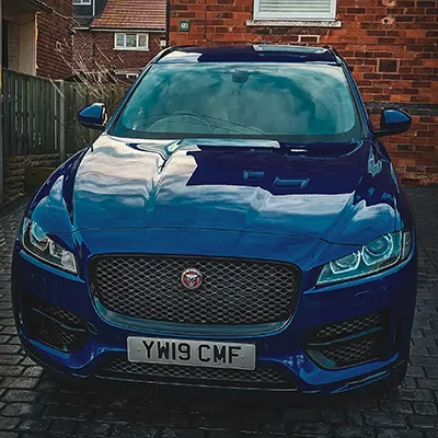 A blue car parked in front of a brick building.