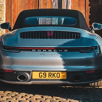 A grey porsche parked in front of a building.