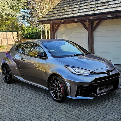 A silver car parked in front of a garage.
