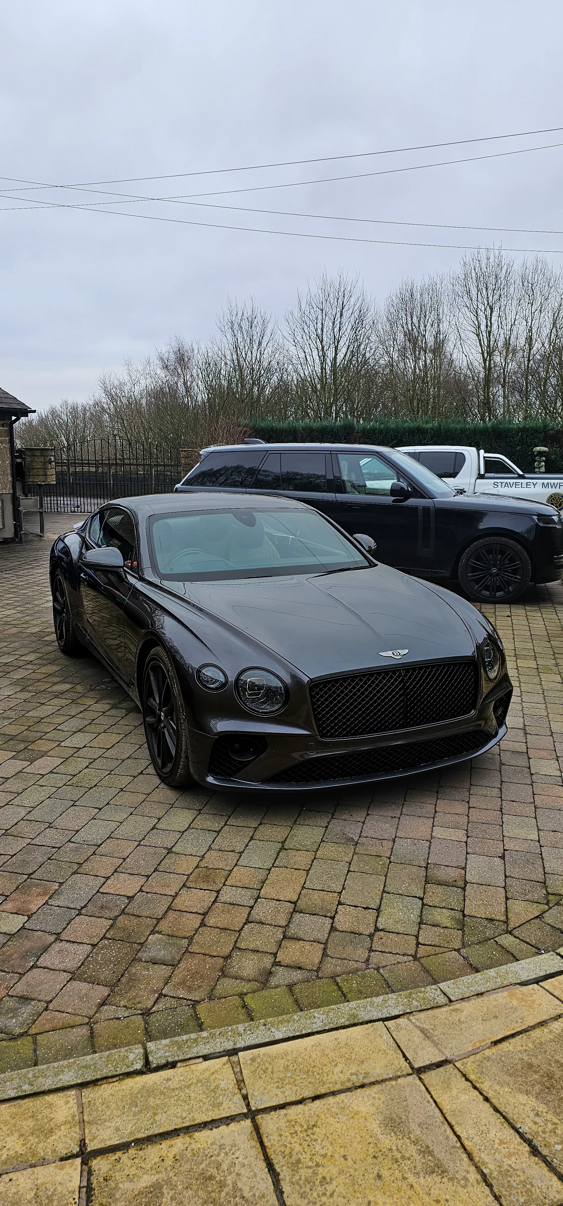 A black car parked in a parking lot next to other cars.