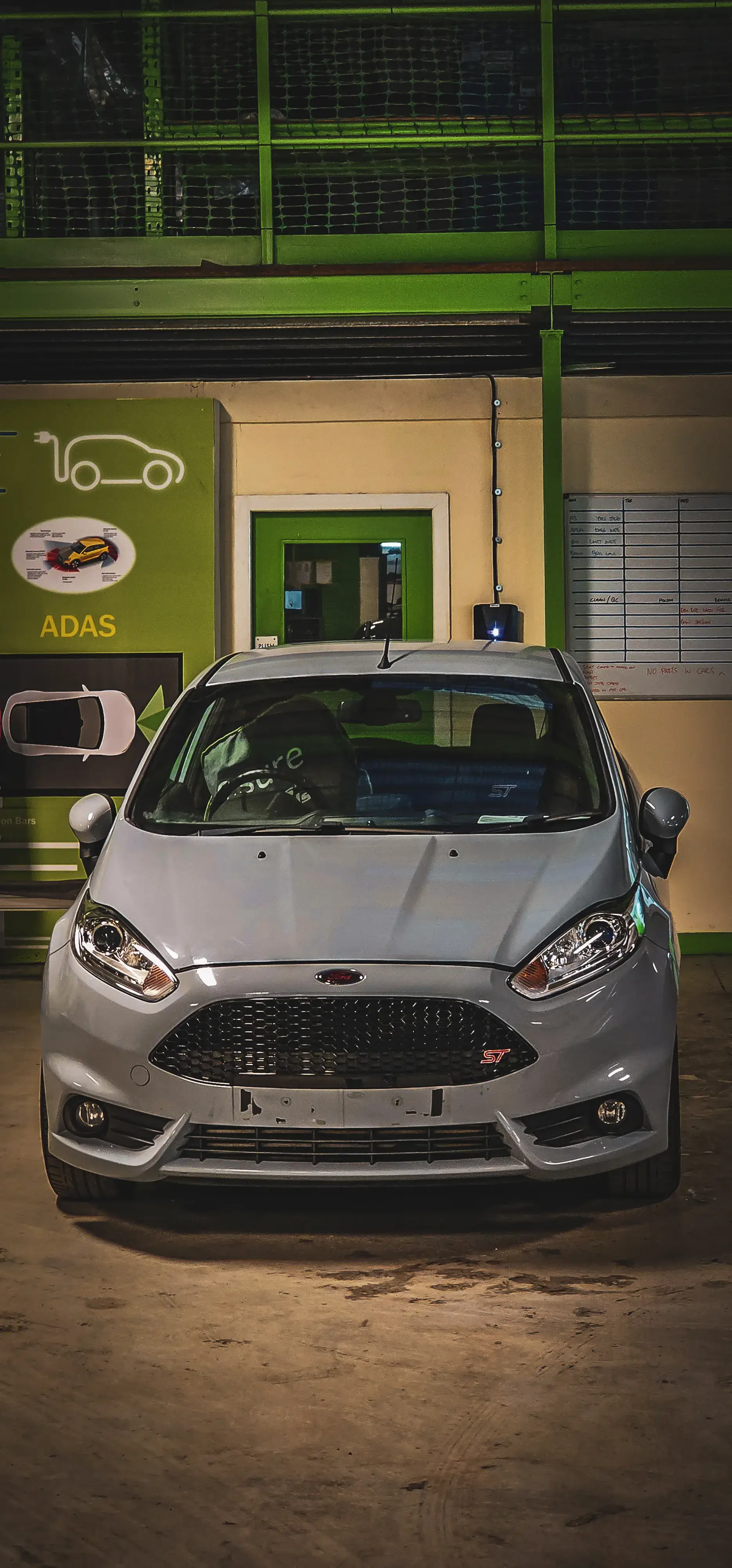A silver car parked in front of a gas station.