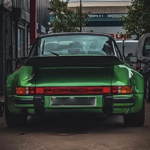 A green porsche parked on the side of the road.