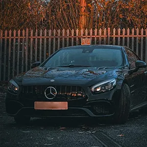 A black car parked in front of a fence.