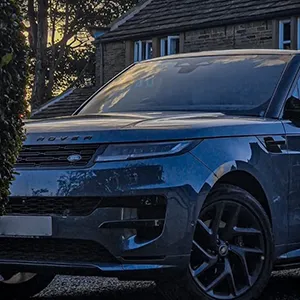 A blue range rover parked in front of a house.